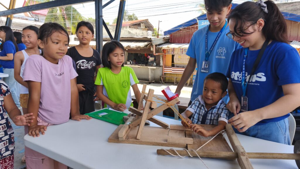 Volunteer students from ATOMS guide children through interactive STEM activities.